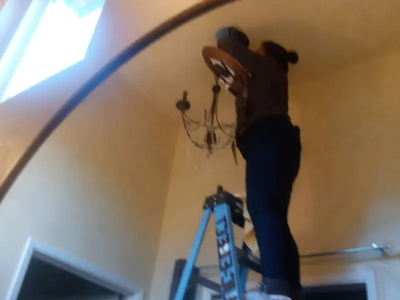 Electrician installing a chandelier in a Dade City residence